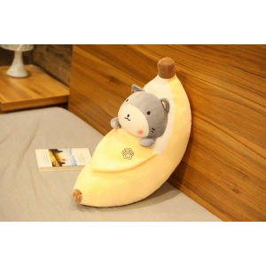 Plysch med skalad banan med en grå shiba inu inuti på en grå säng och en träfärgad vägg med en bok bredvid
