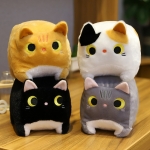 Fyra fyrkantiga kattplyschleksaker på ett träbord. En gul katt på en svart katt och en vit katt på en grå katt.